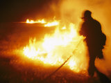 Fire-Fighter Silhouetted against the Flames of a Grass Fire