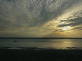 A Boat Speeds Past the Shoreline of the Mackenzie River at Sunset