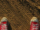 Red Sneakers on Soil Patterned with Tire Tracks