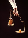 Large and Small Bottles of Generic Pills Being Weighed on Balance Scale