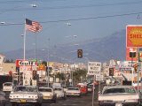 Cars Moving Along Congested Street  Littered with Signs  Billboards and Traffic Directives