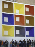 Line of People under Building Facade Painted with Brightly Colored Geometric Pattern