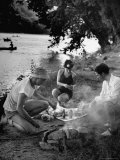 Friends Preparing Their Meal over a Camp Fire