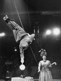 Circus Performer Balancer Unus Standing on His Index Finger on Globe Feet in Air Back of Head