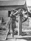 Little Girl Turning Handle on Wheel That Twists Hemp Into Yarn