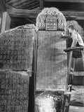 Man Standing on Ladder and Brushing Dust from Large Stone Tablets Covered with Writing