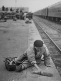 Aged Refugee Fighting Hunger  Sweeps Up Spilled Rice on the Railroad Station Platform