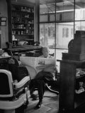 Elderly Barber Sitting Reading the Morning Paper in Small Village Shop in Small New England Town