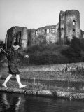 Boy Walking over a Narrow Spit of Land in River in Front of an Old Castle