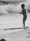 Little Boy Standing on a Surf Board Staring at the Water