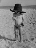 Little Boy at the Beach Wearing a Oversized Cowboy Hat Playing with a Toy Pistol