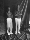 Two Masked Stand Ins Half Clad in Black While Photographed Against Black Backdrop
