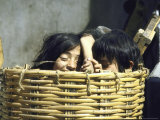 Two Children Playing in Straw Basket at Local Market