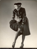 Model Wearing Black Stockings  Fitted Dress Coat  Fur Trimmed Hat and Fur Muff Adjusting Garter