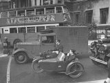 Two Small Military Vehicles Wait For Traffic Light Amid Normal Traffic Near Trafalgar Square