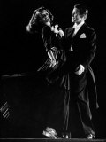 Model Holding Out Skirt of Her Gown as She Dances with Man Wearing Formal Tails
