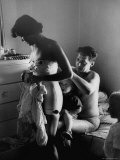 Young Father Helping His Wife Get Dressed as Their Sons Look On