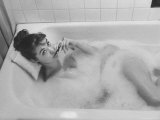 Unexposed Nude Woman in the Bathtub Amid the Bubbles While Smoking a Cigarette