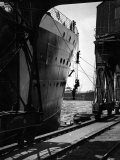 Workers Hanging from Hull of Ship in Hamburg Harbor  in the Midst of Painting It