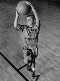 Young Boy Wearing School Gym Clothes Hooting a Basket Ball from the Free-throw Line