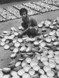 Young Merchant Drying Out Trays Full of Opened Coconuts in His Yard