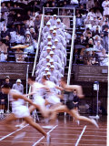 Runners Race by in a Blur as Officials Watch from the Side at the Summer Olympics