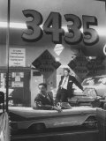 Men Standing in the Window of a Car Dealership