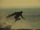 A Surfer and His Board Leap over Breaking Surf