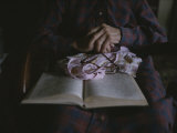 An Old Womans Hands Lie on a Book That She is Reading