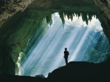 A Man Stands Below the Mouth of a Giant Cave