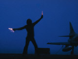 A Ground Control Person Guides a Plane on an Aircraft Carrier