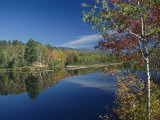 A Lake Surrounded by Trees Displaying the Colors of Autumn