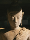 A Statue of Buddha with Eyes Shut Stands in Half Shadow