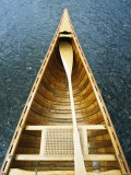 The Bow and Oar of a Handmade Wooden Canoe Resting in Water