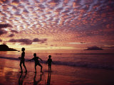 Sunset Reddens a Cloudy Sky as Silhouetted Children Play on the Beach