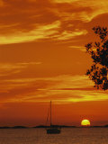 A Sailboat is Silhouetted by a Brilliant Orange Sunset