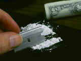 A Hand Dividing up a Pile of Cocaine with a Razor Blade