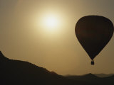 A Hot Air Balloon Rises Above a Hilly Landscape at Sunrise