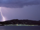 A Lightning Bolt Strikes the Mountains Behind a Town of Costa Brava