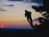 Silhouette of Mountain Biker in the Air against Sunset Sky