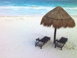 A Palm Frond Umbrella and Two Chairs on a White Sand Beach