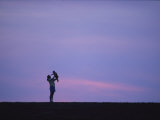 A Mother Holding up Her Baby Sihouetted against a Sky at Sunset