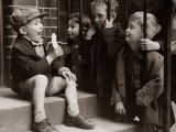 A Little Boy Holding a Banana Whilst Other Children Gaze Longingly at It
