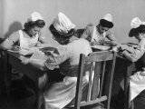Four Young British Student Nurses Making Notes Together from Medical Textbooks