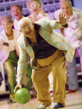 People Watching a Senior Man Bowling at a Bowling Alley
