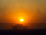 An American Humvee Drives Through the Desert at Sunset Near the Iraqi Border