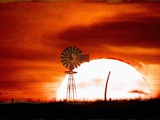 A Blazing Sun Drops Behind a Windmill