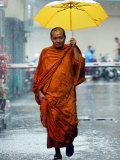 A Buddhist Monk Walks in the Rain on a Street in Bangkok