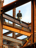 A Construction Worker Stands on a Steel Beam While Working on a High Rise Building
