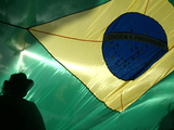 A Vendor Walks Behind a Big Brazilian Flag